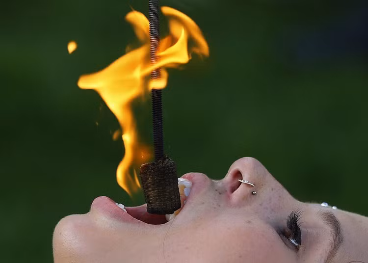 Street performer Kristin Decker performs a fire-eating act before the opening ceremonies for the 2013 Presidents Cup golf tournament in Columbus.