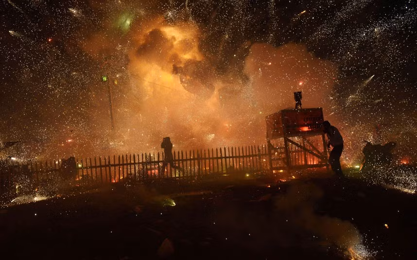 People protect themselves from fireworks which accidentally exploded before the balloon carrying them got enough height during a hot air balloon festival in Taunggyi in Myanmar’s northeastern Shan state