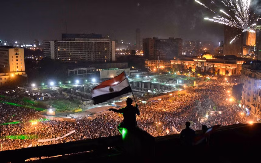 Biển người có mặt tại quảng trường Tahrir (Ai Cập) phản đối Tổng thống bị lật đổ Mohammed Morsi Egyptians wave the national flag from a building rooftop as hundreds of thousands flood Cairo