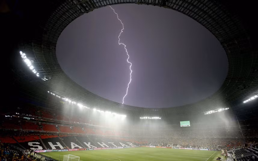 A bolt of lightning streaks across the sky above the Donbass Arena in Donetsk after the Euro 2012 match between France and Ukraine was suspended due to bad weather