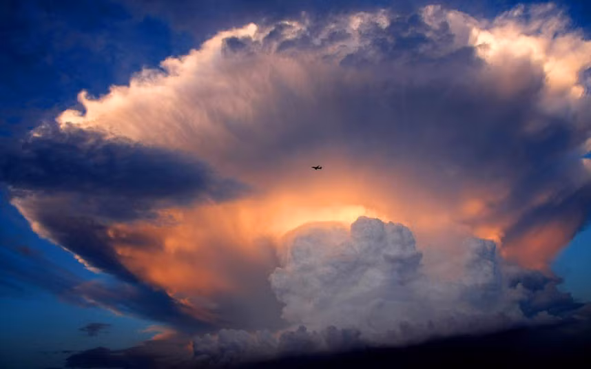 A jet plane flies past a mushroom-like cumulonimbus storm cloud over Beijing, China