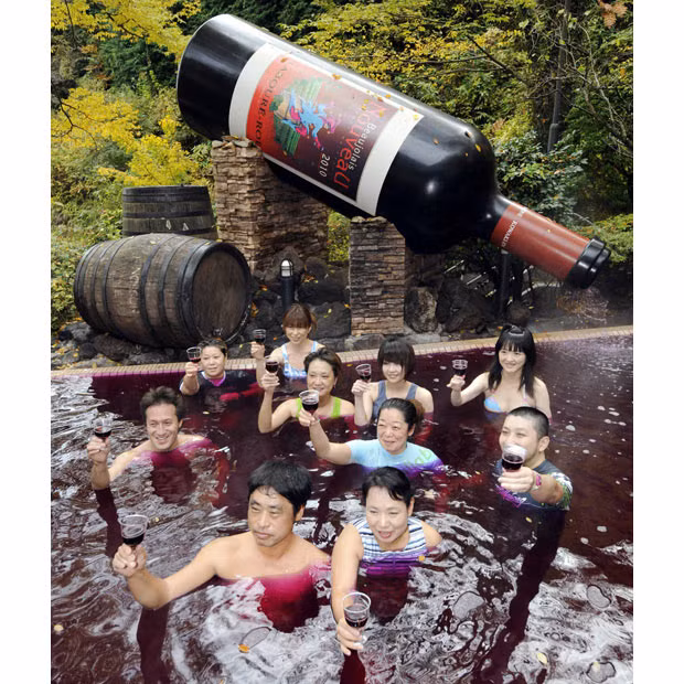 Visitors hold up their glasses to toast with 2010 Beaujolais Nouveau wine at a wine spa at the Hakone Yunessun spa resort facilities in Hakone, Kanagawa prefecture, Japan