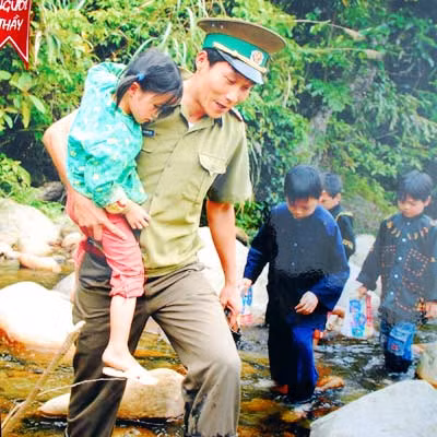 Thầy giáo mang quân hàm xanh bế HS qua suối đến lớp. Ảnh: Văn Thọ Thầy giáo mang quân hàm xanh Nguyễn Việt Lợi Ảnh: Văn Thọ
