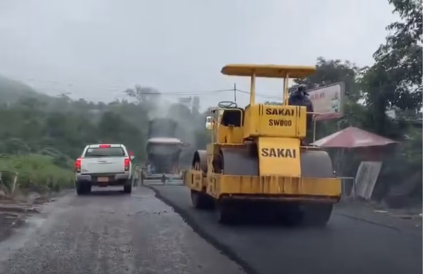 Đơn vị thi công thảm nhựa mặt đường quốc lộ 15D khi trời mưa. Ảnh: Khắc Trà