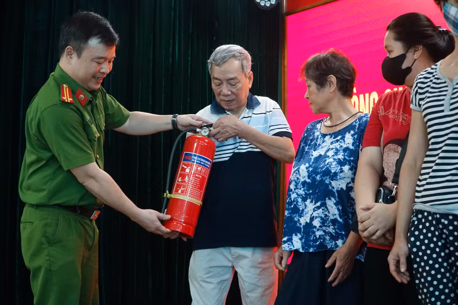Trung Tá Nguyễn Hùng An, Đội phó Đội PCCC&amp;CNCH Công an quận Ba Đình tặng bình chữa cháy cho các thành viên của Tổ liên gia PCCC.