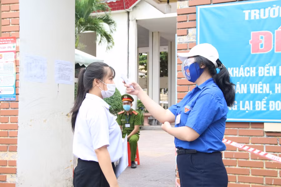 Tình nguyện viên đo thân nhiệt cho thí sinh trước khi vào phòng thi.