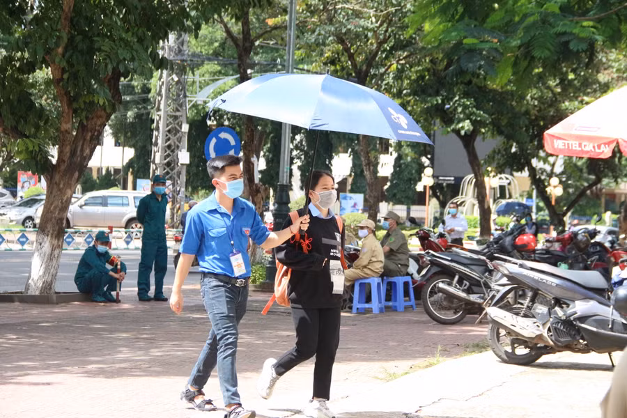 Tình nguyện viên che dù, đưa thí sinh vào điểm thi.