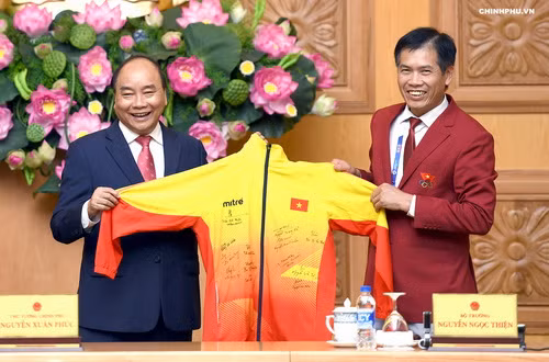 Thủ tướng nhận qùa là đồng phục của đội tuyển Việt Nam có các chữ ký của các vận động viên đạt huy chương tại giải thể thao Asiad 