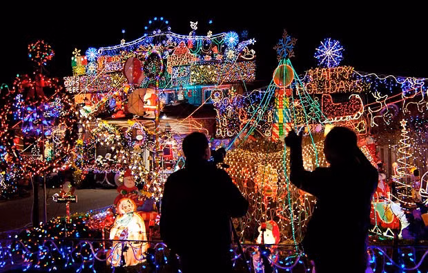 People take photos of colourful Christmas lights in front of a house in Toronto, Canada