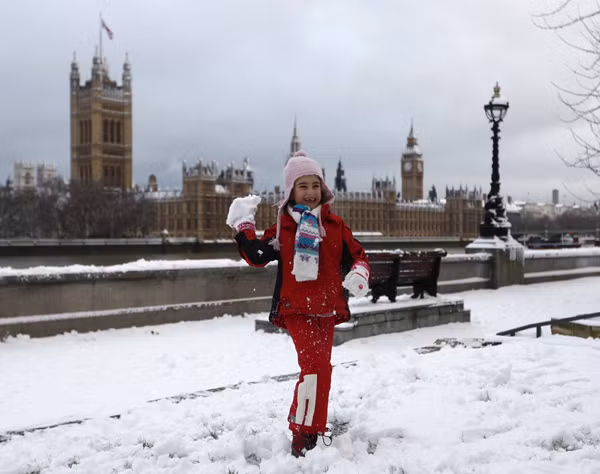 A young girl throws a snowball while posing for a photograph opposite the Houses of Parliament, in central London December 18, 2010. Fresh snow brought much of Britain to a standstill on Saturday, on what is traditionally the busiest weekend for shopping and travel in the run-up to Christmas. 