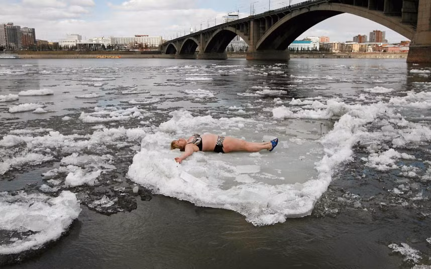 Những hình ảnh ấn tượng trong tuần ảnh 5 A member of the Cryophil winter swimmers club lies on floating ice on the Yenisei River in the Siberian city of Krasnoyarsk