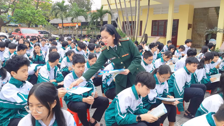 Cán bộ phát tờ rơi tuyên truyền về Luật Biên phòng Việt Nam cho học sinh.