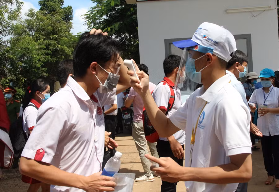Các em học sinh được đo nhiệt độ, sát khuẩn trước khi vào trường.
