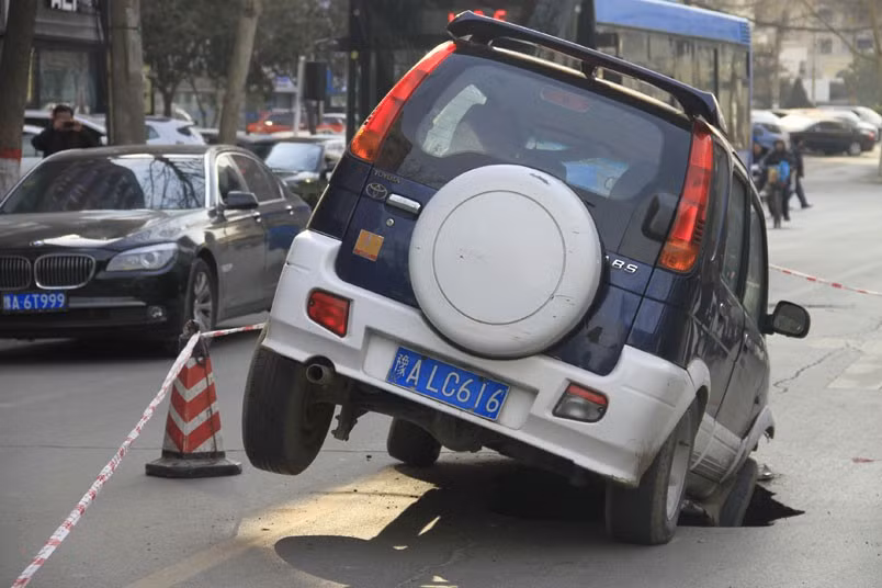 A car is trapped in a hole after a road caved in, in Zhengzhou, China