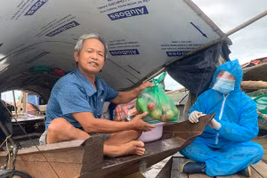Chị Thanh đem các phần nhu yếu phẩm tặng người dân xóm chài ven sông Hồng. Nguồn: Zing.