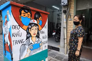 Người dân xem những bức tranh cổ động về công tác phòng chống dịch Covid-19. Ảnh: TTXVN.