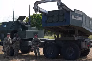 Binh sĩ quân đội Mỹ đứng cạnh bệ phóng hệ thống tên lửa pháo binh cơ động cao (HIMARS). (Ảnh: AFP)