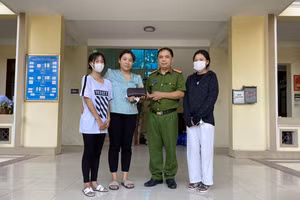 Đại diện công an xã Song Khê cùng hai em học sinh trao trả lại hiện vật cho người bị mất. 
