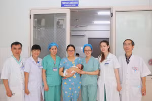 Mẹ và cháu bé sơ sinh bị bệnh xoắn nghẹt ruột non hiếm gặp (giữa) chụp ảnh cùng các y bác sĩ Bệnh viện Trung ương Huế ngày ra viện. (Ảnh: T.H.)