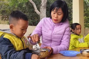 Bé Vi Thanh Hà đang được cô giáo chăm sóc trong bữa ăn tại trường.