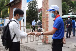 Tình nguyện viên tại Kon Tum sát khuẩn cho thí sinh trước khi vào phòng thi trong Kỳ thi tốt nghiệp THPT 2020.