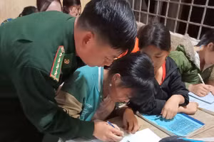 Thầy Di cầm tay dạy học trò viết chữ. (Ảnh: NT)