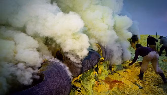 Hơi nước và khí axit bốc lên từ những lỗ phun khí nằm giữa những tảng lưu huỳnh màu vàng và lưu huỳnh lỏng đang cháy. Lưu huỳnh được sử dụng rộng rãi trong nhiều ngành công nghiệp chế biến như cao su, tẩy trắng đường, phân bón.... Ảnh: BBC.
