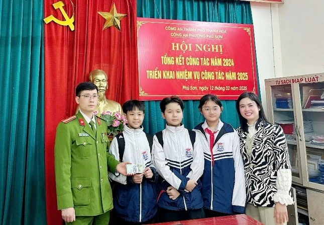 Ba học sinh trong số bốn học sinh nhặt được bọc tiền cùng cô giáo đến giao lại cho cơ quan công an.