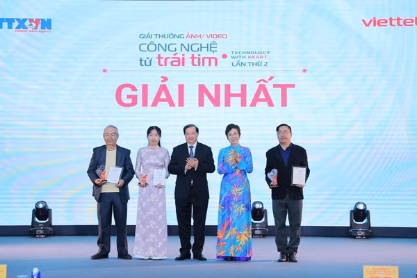 Tổng Giám đốc TTXVN Vũ Việt Trang, Chủ tịch Hội đồng Giải thưởng và Thứ trưởng Bộ Văn hóa, Thể thao và Du lịch Tạ Quang Đông trao giải Nhất cho các tác giả. (Ảnh: Lê Đông - TTXVN)