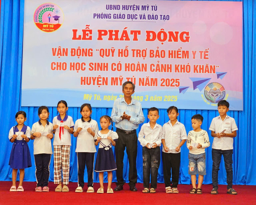 Ông Nguyễn Thanh Phong, Phó Chủ tịch UBND huyện Mỹ Tú (Sóc Trăng) trao thẻ bảo hiểm cho các em học sinh. (Ảnh: Xuân Lương)