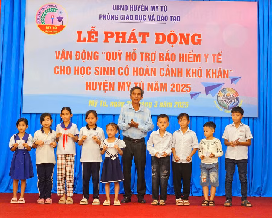Ông Nguyễn Thanh Phong, Phó Chủ tịch UBND huyện Mỹ Tú (Sóc Trăng) trao thẻ bảo hiểm cho các em học sinh. (Ảnh: Xuân Lương)