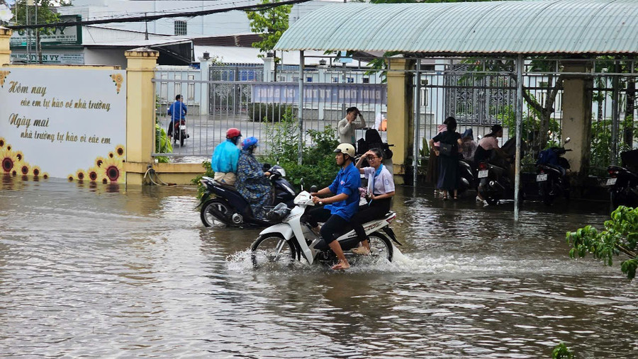 Tình nguyện viên lái xe máy chở thí sinh vượt vùng ngập nước. Ảnh: Minh Hoàng. img-20250627-080952.jpg