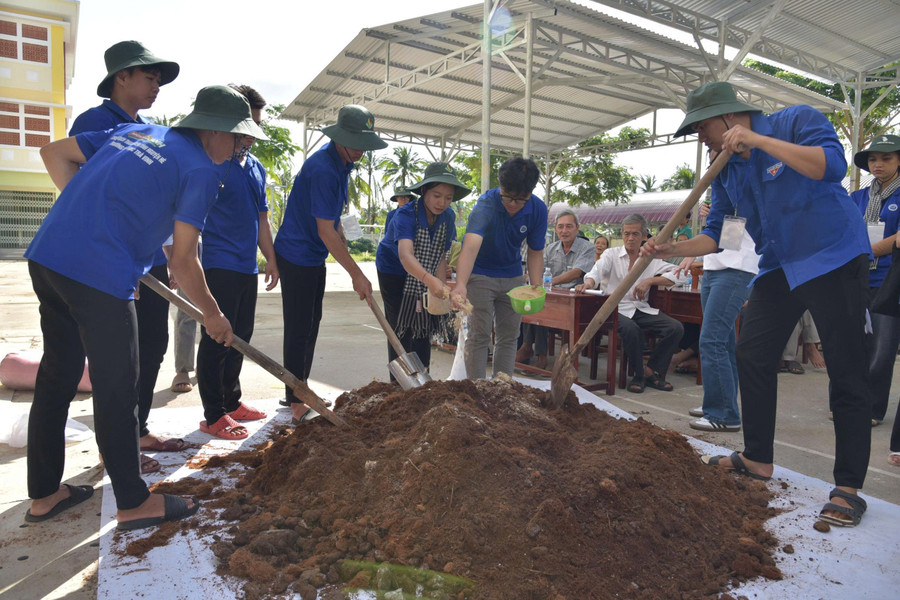 Sinh viên Trường Đại học Trà Vinh hướng dẫn bà con làm phân hữu cơ. Ảnh: Bình An