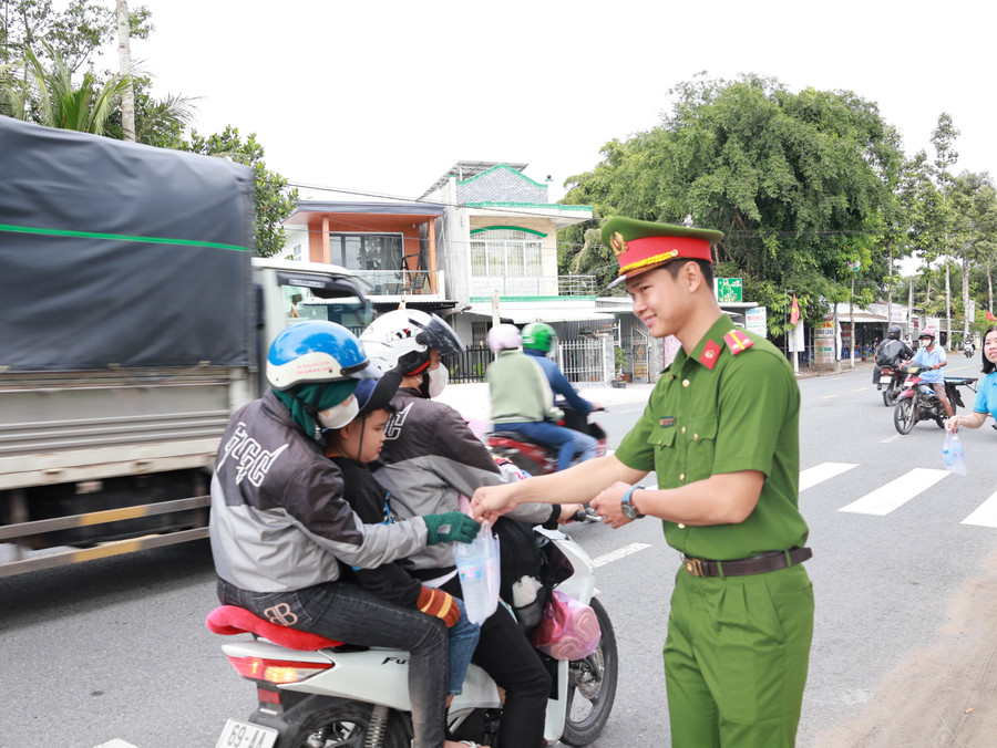 Cán bộ, chiến sĩ Công an phát nước suối và khăn lạnh cho người dân về quê nghỉ lễ.