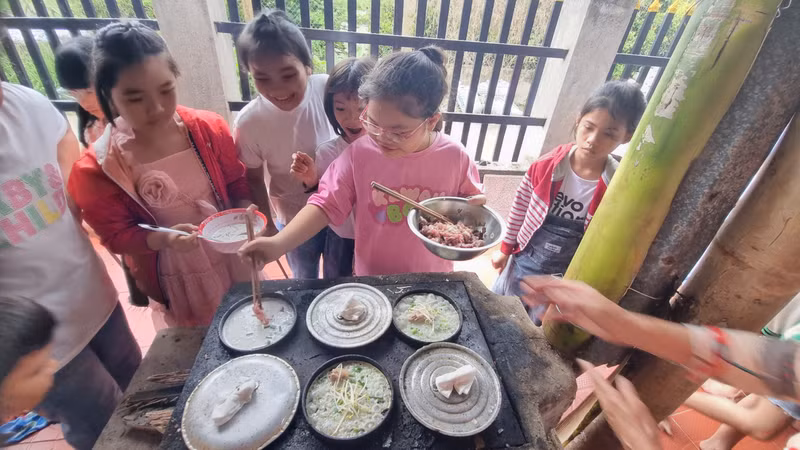 đến thực hành đổ bánh xèo trên khuôn. Học sinh thích thú trải nghiệm làm bánh truyền thống ở làng du lịch