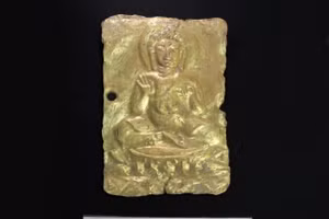 Một tấm phù điêu vàng miêu tả Phật ngồi kết già trên tòa sen.