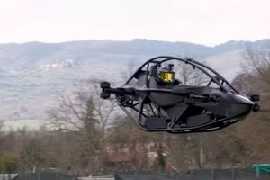 Máy bay eVTOL Jetson ONE đang bay giữa không trung trên một cánh đồng với dãy núi phía sau. Ảnh: Jetson
