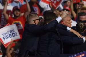 Ông Trump được nhân viên mật vụ bao quanh sau khi có tiếng súng vang lên tại một cuộc vận động tranh cử ở Butler, Pennsylvania. Ảnh: AFP / Jeff Swensen