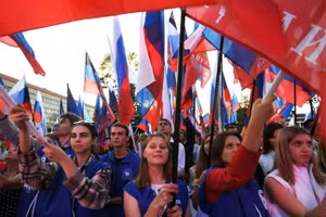 Người dân giương cao cờ Nga tại một cuộc biểu tình ở Simferopol, Nga, để ủng hộ việc sáp nhập các vùng Donetsk, Lugansk, Kherson và Zaporozhye vào Nga ngày 30/9/2022. Ảnh: © Konstantin Mikhalchevsky / Sputnik