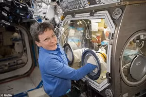 Phi hành gia NASA Peggy Whitson dừng lại chụp ảnh khi đang làm việc bên trong Microgravity Sciences Glovebox.