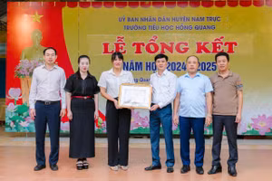 Giám đốc Sở GD&ĐT Nam Định Nguyễn Xuân Hồng trao Giấy khen cho hành động dũng cảm cứu người của cô Nguyễn Thị Mai. Ảnh: Nhà trường cung cấp. 