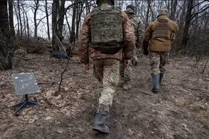 Binh sĩ Ukraine đi qua một thiết bị đầu cuối internet vệ tinh Starlink.