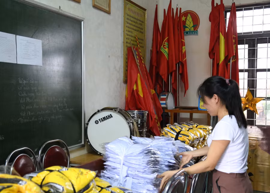 Cán bộ trường THCS Lý Trạch chuyển áo quần, thiết bị lên chỗ cao ráo tránh ngập nước
