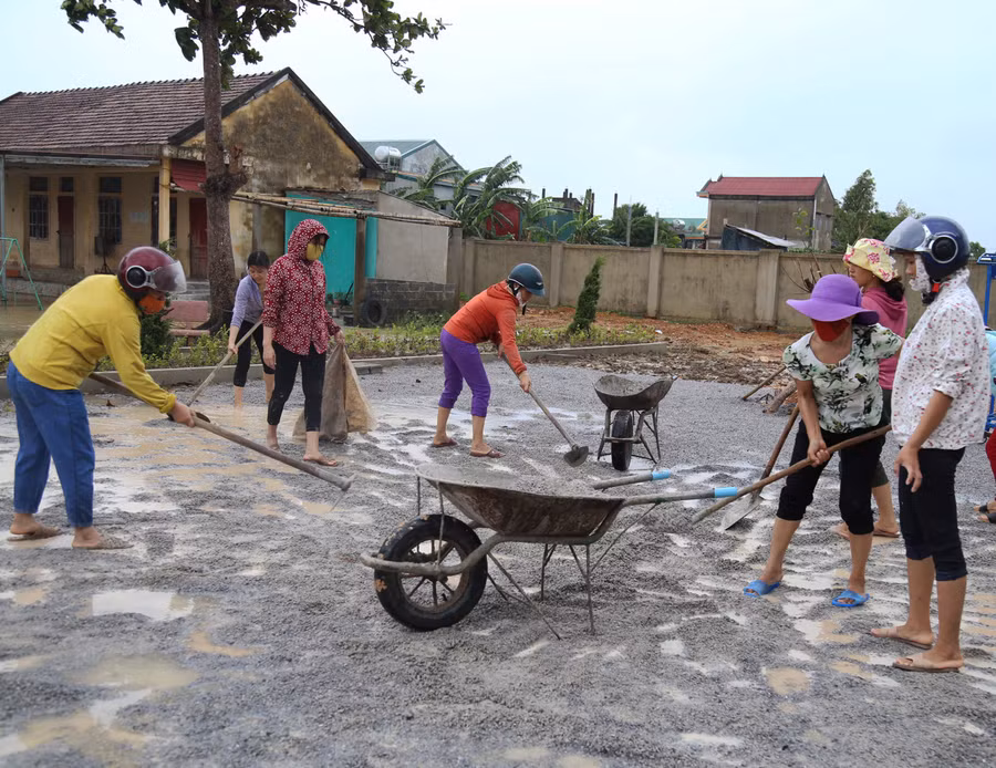 Các giáo viên trường Mầm non An Ninh đội mưa để san lấp mặt bằng sân trường.