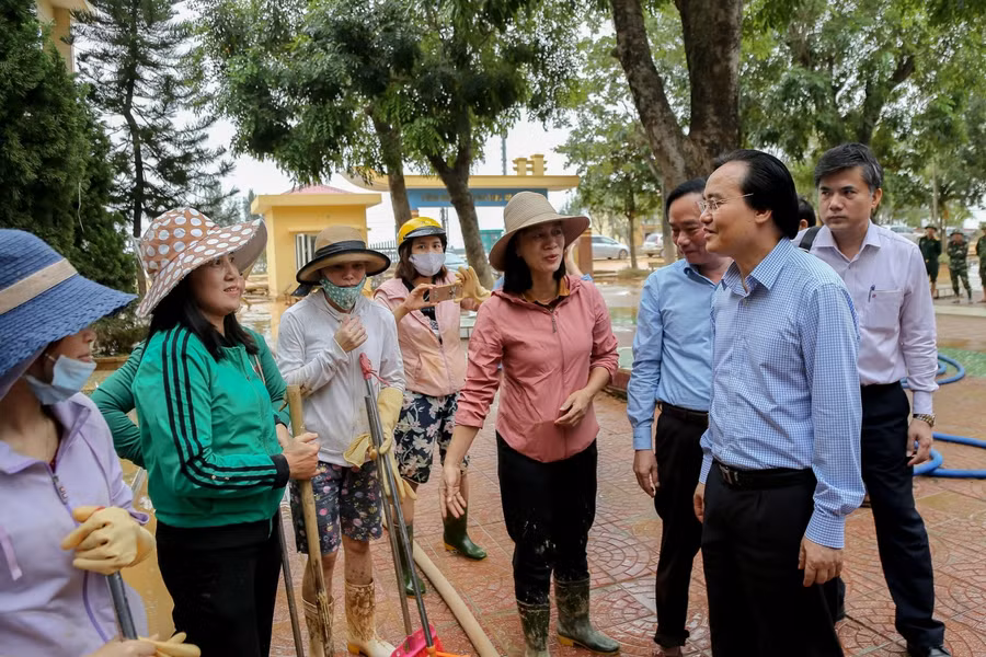 Bộ trưởng Phùng Xuân Nhạ động viên các thầy cô đang dọn vệ sinh trường lớp sau lũ.