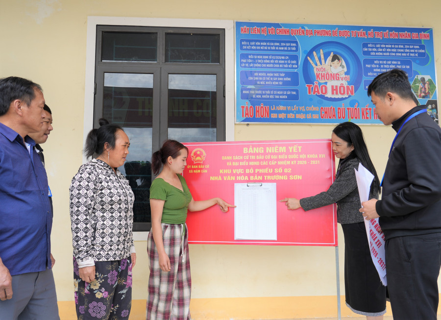 Cán bộ xã Nậm Cắn (Nghệ An) hướng dẫn người dân bản Trường Sơn đọc thông tin danh sách cử tri ở điểm bầu cử. Ảnh: Hồ Lài