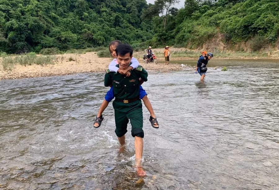 Cán bộ chiến sĩ Đồn Biên phòng Hướng Lập cõng các em vượt suối đến trường khai giảng.