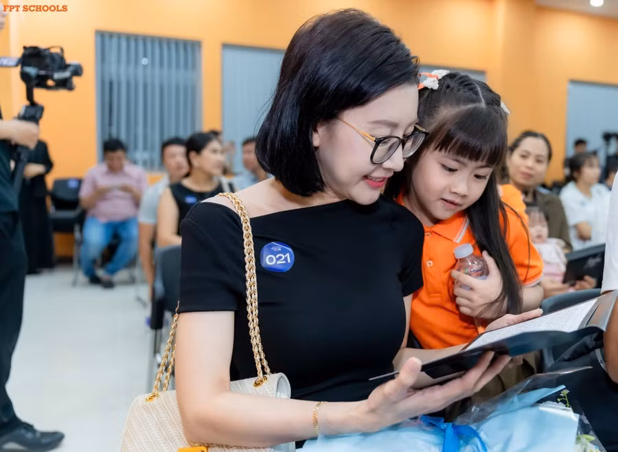 Phụ huynh cùng con xem thư tay nhà trường gửi nhân dịp bế giảng năm học.