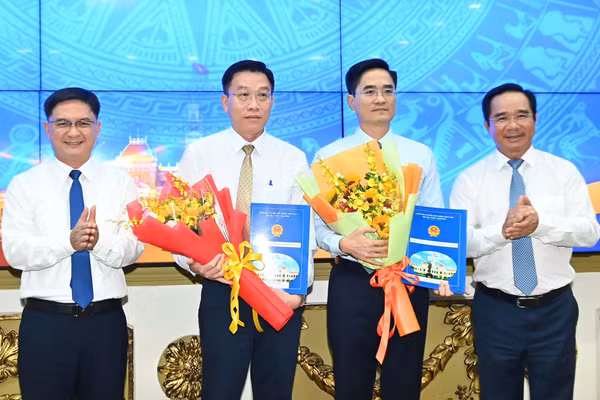 Ông Trần Quang Lâm, Giám đốc Sở Xây dựng TPHCM (thứ 2 từ phải sang) và ông Nguyễn Anh Minh, Giám đốc đốc Ban Quản lý dự án đầu tư xây dựng các công trình giao thông TPHCM nhận quyết định bổ nhiệm từ lãnh đạo UBND TPHCM. (Ảnh: SGGP)