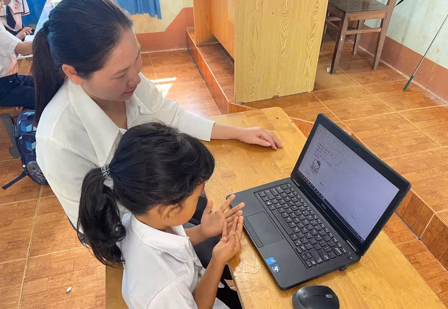 Giáo viên phân hiệu Trường Tiểu học Đinh Tiên Hoàng hỗ trợ các em làm quen và thực hành trong môi trường số bằng máy tính cá nhân. Ảnh: Thế Hùng